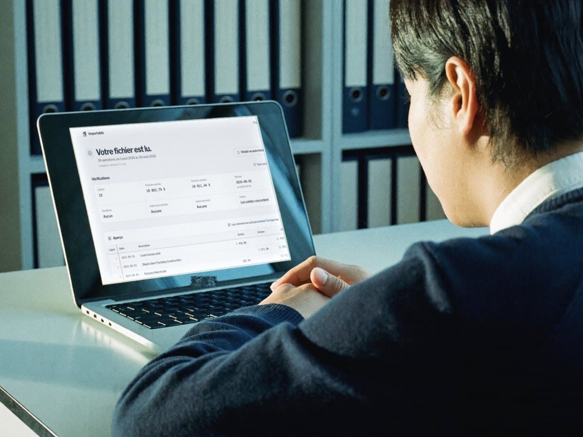 A bookkeeper at a desk, hands clasped, reading the checks on the laptop.