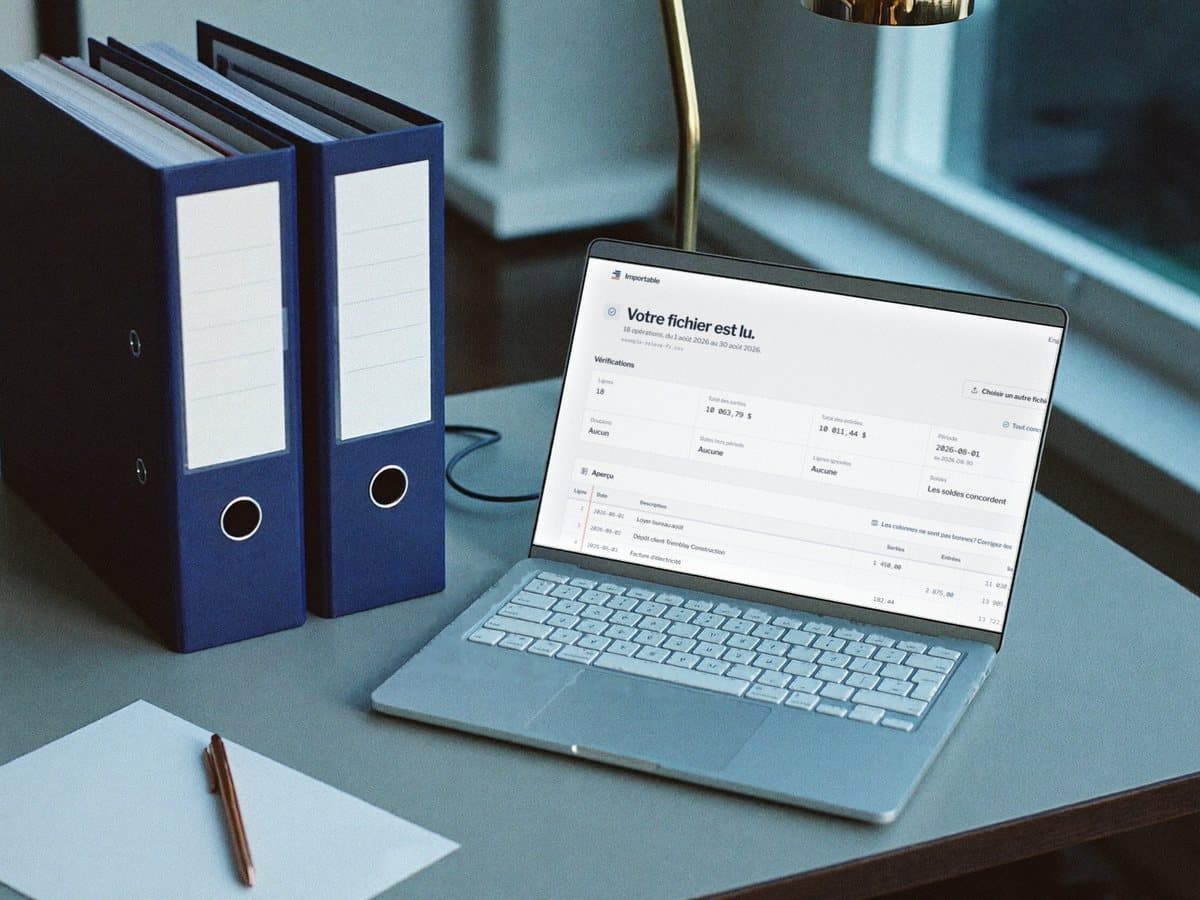 A bookkeeper's desk at month end: navy binders, and a laptop showing the checks on a fictional statement, with the balances matching.