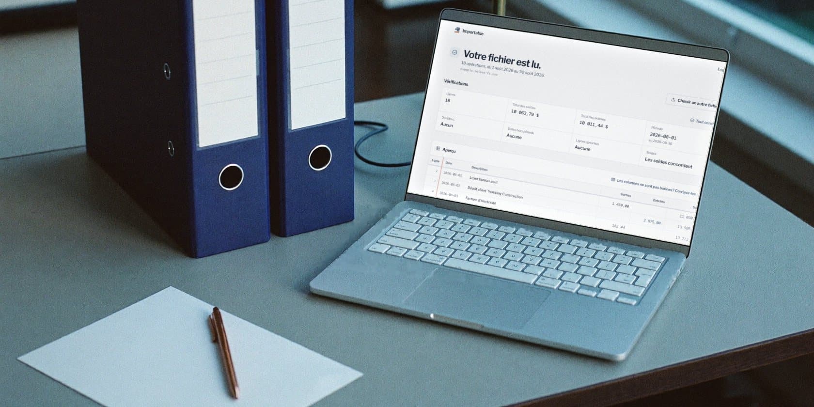 A bookkeeper's desk at month end: navy binders, and a laptop showing the checks on a fictional statement, with the balances matching.